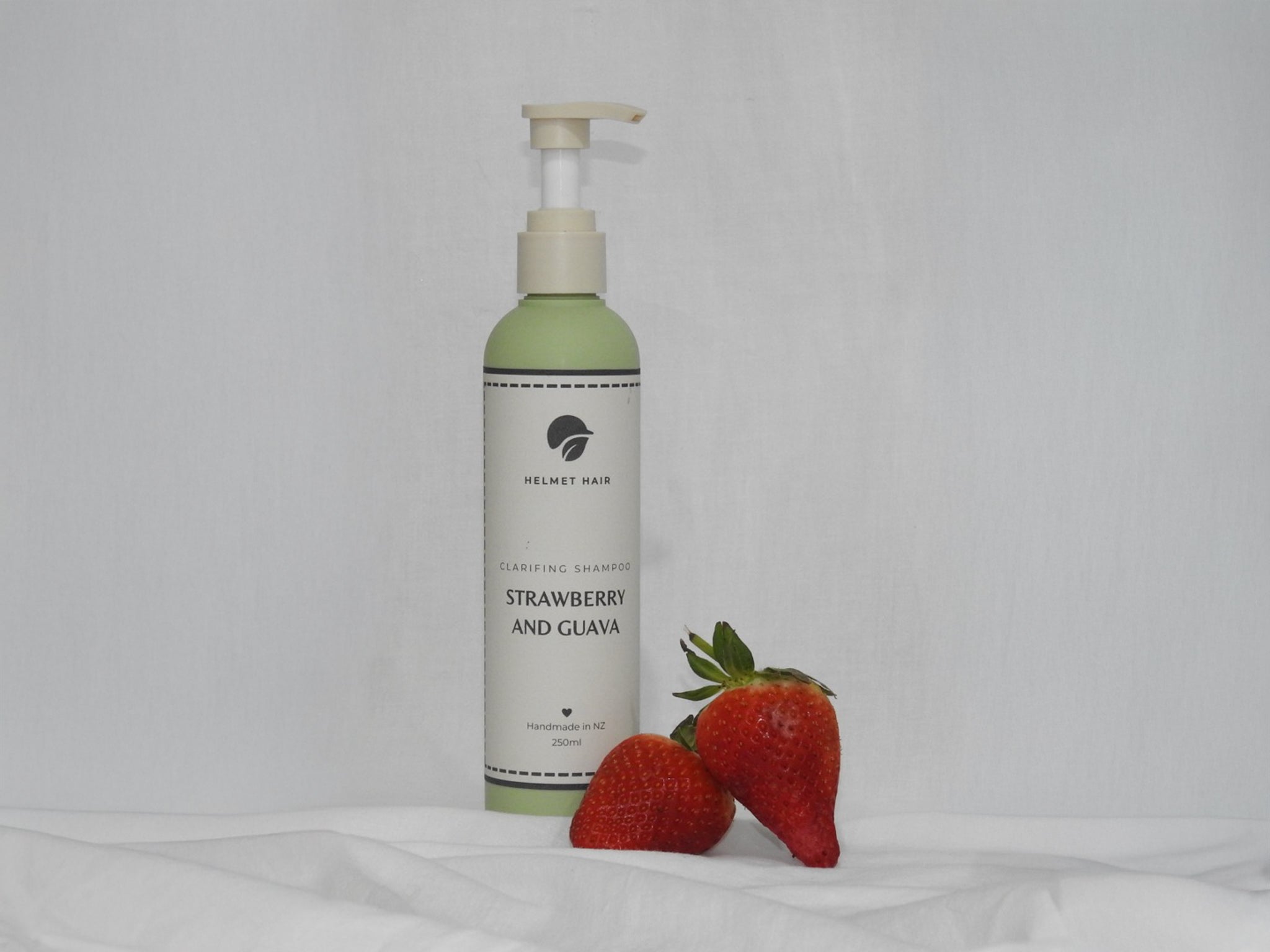 Bottle of strawberry and guava product with two strawberries on a white background